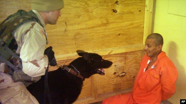 This image obtained by The Associated Press shows Sgt. Michael Smith, left, with his dog, watching a detainee at an unspecified date in 2003 at the Abu Ghraib prison in Baghdad, Iraq.