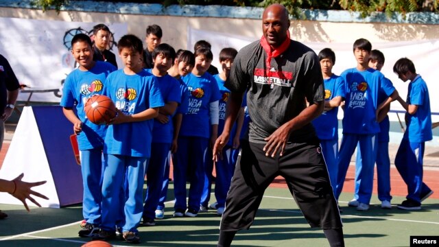 FILE - Lamar Odom of NBA basketball team Los Angeles Clippers shows a group of children how to pass the ball during a coaching clinic at the Huangzhuang School in Beijing, China, Oct. 10, 2012. 