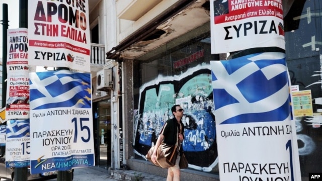 A man passes by election posters of the conservative new Democracy party and the left coalition Syriza party in central Athens, June 13, 2012.