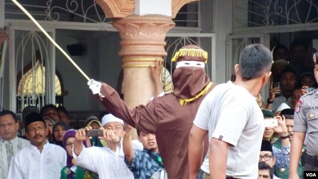 Algojo pelaksana cambuk mengayunkan rotan ke punggung pelanggar hukum syariah di Banda Aceh (19/9). (VOA/Budi Nahaba)