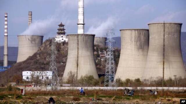 Fishermen sit beside a lake in front of the chimneys of a coal-burning power station located on the outskirts of Beijing, November 22, 2011.