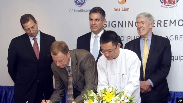 President and CEO of General Electric ASEAN, Stuart Dean, second from left, signs documents during the signing ceremony between Sea Lion Co. Ltd., General Electric Healthcare and Bahosi and Pun Hlaing Hospitals in Rangoon, Burma, July. 14, 2012. 