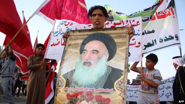 Một người đàn ông Iraq đem theo bức chân dung Đại giáo sĩ Ayatollah Ali al-Sistani, lãnh đạo tinh thần của người Shia, khi người dân tập trung bày tỏ quyết tâm xin tham gia lực lượng an ninh Iraq trong cuộc chiến chống các phần tử chủ chiến Jihad, 19/6/2014