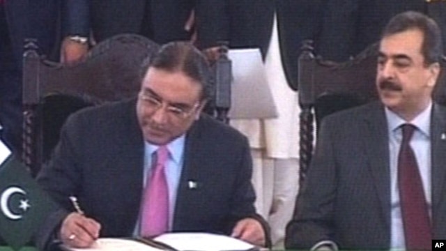 Pakistan's President Asif Ali Zardari, left, signs a constitutional reforms law as Prime Minister Yousuf Raza Gilani  looks on during a ceremony in Islamabad, 19 Apr 2010