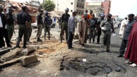 Security officials assess the scene of a suspected Boko Haram bomb attack that killed four people in Nigeria's northern city of Kaduna, April 8, 2012. 