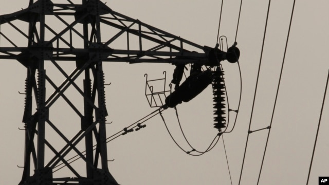 In this Saturday, Feb. 8, 2014 photo, linemen are silhouetted as they work to restore electrical power, at an electric pole in Krang Thnong at the outskirt of Phnom Penh, Cambodia. (AP Photo/Heng Sinith)