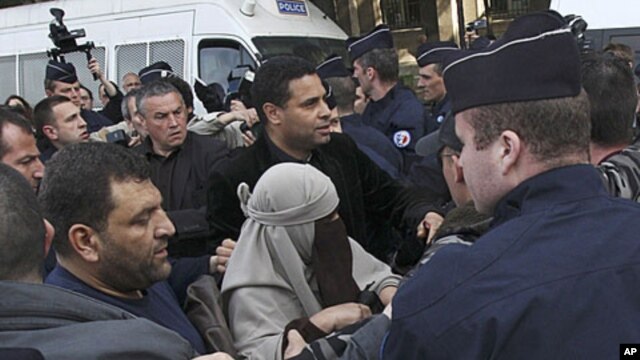 An unidentified veiled woman is taken away by plain clothed and uniformed police officers in Paris, Monday, April 11, 2011