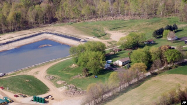 June Chappel’s home in Washington, Pennsylvania, is surrounded by gas drilling: a waste containment pond behind her and gas tanks to the side.