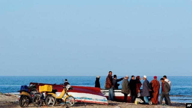Tunisian people stand at the seaside in coastal town Zarzis in southeastern Tunisia, February 18, 2011
