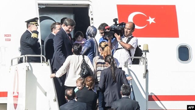 Thủ tướng Thổ Nhĩ Kỳ Ahmet Davutoglu (trái) vào máy bay với các con tin ngày 20/9/2014, tại sân bay ở thành phố Sanliurfa, miền nam Thổ Nhĩ Kỳ, gần biên giới Syria.