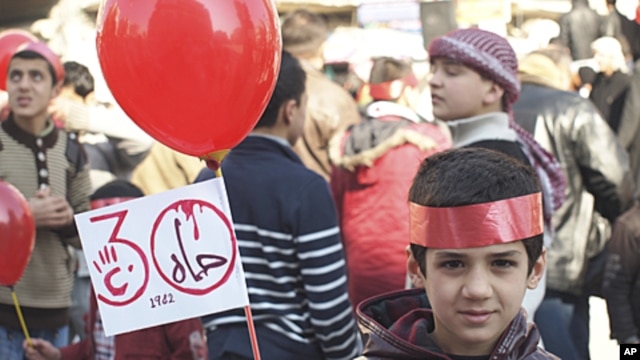 A young boy holds up a sign that reads, "Hama 1982," during a protest against Syria's President Bashar al-Assad after Friday prayers in Idlib February 3, 2012.