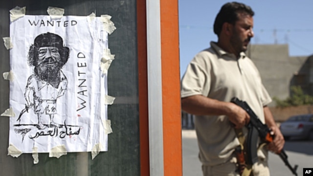 A rebel fighter stands next to an image representing Moammar Gadhafi at a checkpoint in Tripoli, Libya, August 30, 2011