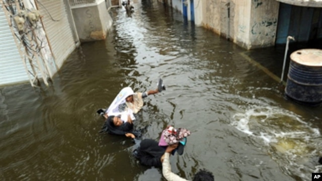 Pakistani men wade through floodwaters in Sujawal in southern Sindh province, Pakistan, 30 Aug 2010.  Floodwaters have begun to recede in the northwest and central parts of Pakistan.