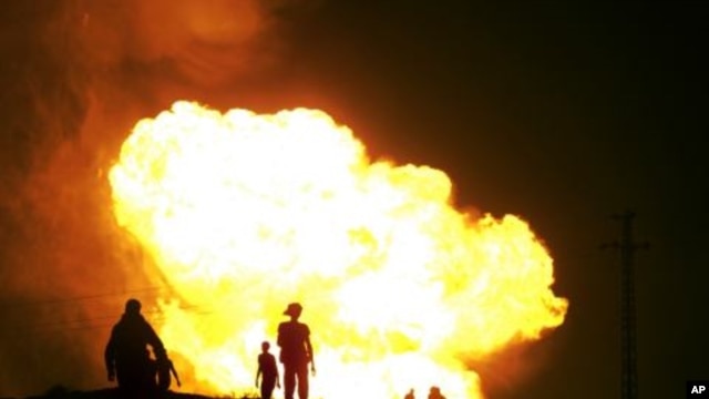 Egyptians watch as smoke and flames rise into the air after masked gunmen blew up a terminal of the Egyptian natural gas pipeline to Israel and Jordan in el-Arish, in the northern part of Egypt's Sinai Peninsula, in a predawn attack, July 12, 2011.