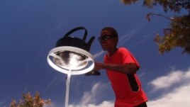 A boy tends a kettle boiling one on of the parabolic cookers (Photo: Sunfire)