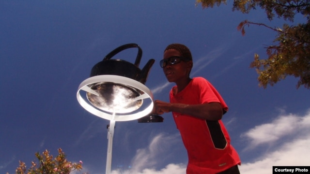 A boy tends a kettle boiling one on of the parabolic cookers (Photo: Sunfire)