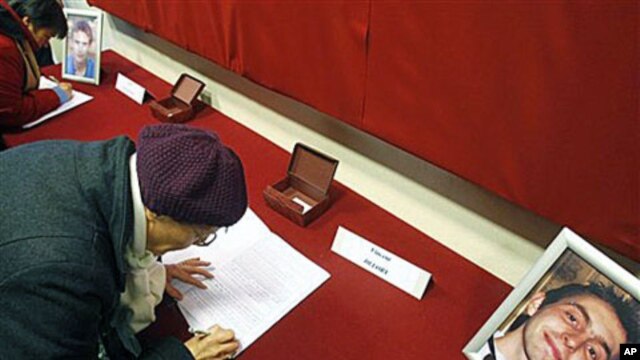 Residents sign a condolence book for Antoine De Leocour, in photo, and Vincent Delory in Linselles, northern France, Jan 10, 2011