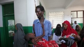 Un déplacé portant son enfant victime du choléra