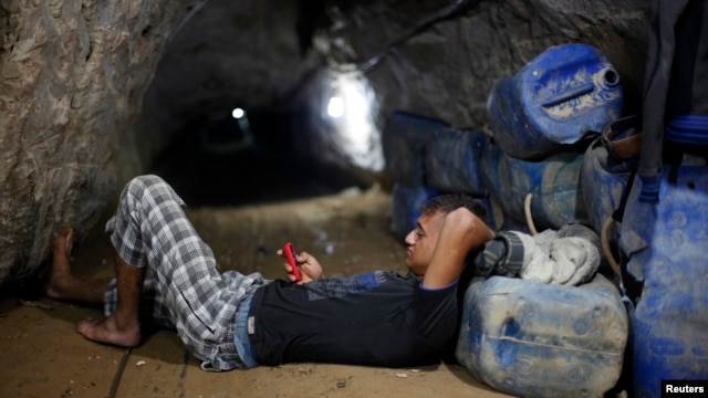 A Palestinian tunnel worker uses his mobile as he rests inside a smuggling tunnel beneath the Gaza-Egypt border in the southern Gaza Strip, July 19, 2013. 