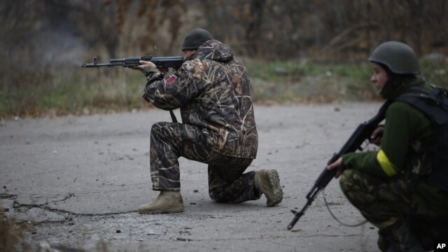 FILE - Ukrainian volunteer fighters are seen holding their weapons in the village of Peski, near Donetsk, eastern Ukraine, Nov. 12, 2014.