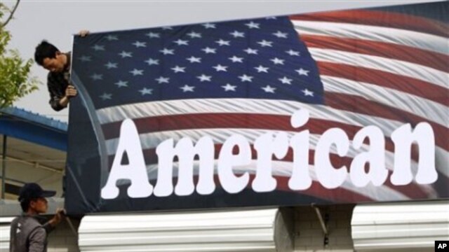 Chinese workers set up a signboard for a shop selling American motorcycles in Beijing, April 16, 2011
