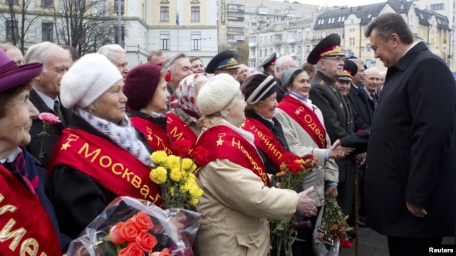 Ukrainian President Viktor Yanukovich (R) greets veterans during a ceremony to mark the day of Ukraine's liberation from Nazi invaders during World War II on the day of the parliamentary elections in Kiev, October 28, 2012.