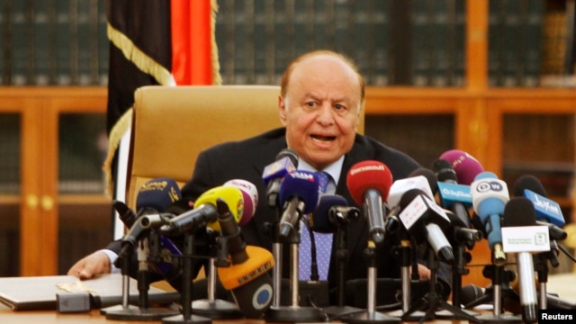FILE - Yemen's President Abd-Rabbu Mansour Hadi speaks as he holds an agreement (L) signed between the government and Houthi rebels, in Sanaa, Sept. 21, 2014.