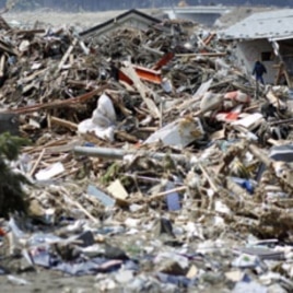 A survivor walks through debris in Rikuzentakata, Iwate prefecture, where the earthquake and tsunami hit last week, March 18, 2011