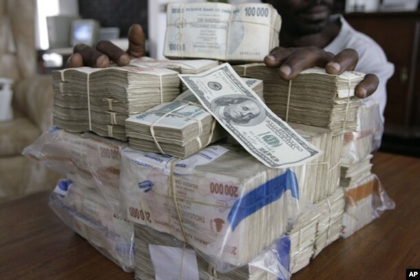 FILE: An unidentified man displays the equivalent of 100 United States dollars on a scale in Harare, Wednesday, March, 5, 2008. The Zimbabwean currency was abandoned in 2009 due to hyperinflation.