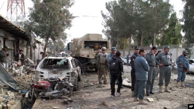Afghan policemen investigate the scene of a deadly attack in Lashkar Gah, Helmand province on January 26, 2012. A suicide car bomber targeted a NATO convoy of armored vehicles, killing four people and wounding dozens of others.