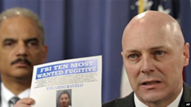 FBI Executive Assistant Director Shawn Henry (r) holds up a wanted poster during a news conference in Washington with Attorney General Eric Holder, March 9, 2011