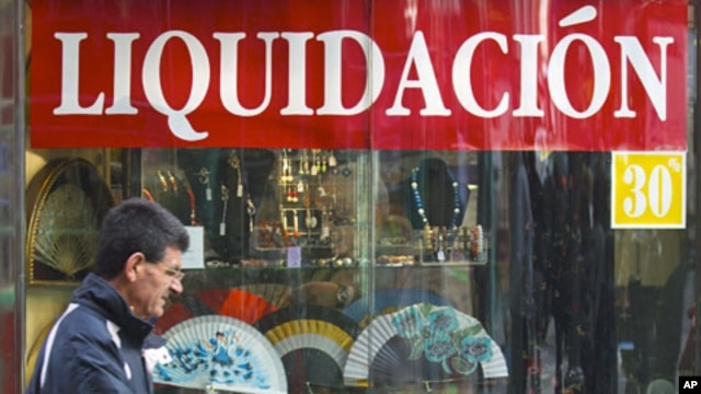 A man walks past a shop selling Spanish fans with a sign reading 'Liquidation' during early sales in Madrid, January 2, 2012