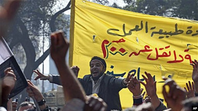 Public transportation workers protest in demand of salary raises in front of the national TV building, right, in Cairo, Egypt, February 14, 2011
