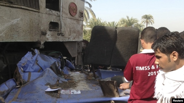 Relatives of victims look at the wreckage of a bus after a train crashed into it in Assuit province, some 300 kilometers south of Cairo, November 17, 2012.