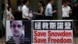 People carrying mobile phones walk past a banner supporting Edward Snowden, a former contractor at the National Security Agency (NSA), at Hong Kong's financial Central district, June 18, 2013. 