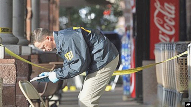 An FBI agent writes down information as he looks at a chair and the ground where Rep. Gabrielle Giffords was shot at a local Safeway in Tucson, Arizona, 10 Jan 2011