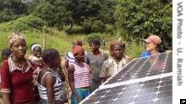 Des villageois dans le District de Kalale scrutant un panneau solaire nouvellement installé. 