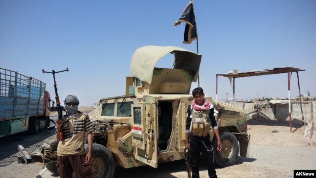 Militantes del Estado islámico junto a un vehículo militar iraqui capturado.