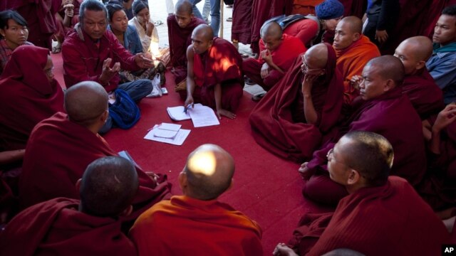Activist known as Ko Kyaw, left background in blue pants, gestures during a meeting with protesting Buddhist monks who occupy the office entrance to the Chinese copper mine company Wan Bao Co. Ltd in northwestern Myanmar, Wednesday, Nov 28, 2012.