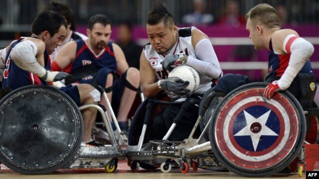 Japan's Shin Nakazato (C) holds onto the ball as Chuck Aoki of the US (L) closes in during the bronze medal Wheelchair Rugby match between USA and Japan, in London, September 9, 2012. 