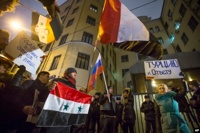 Người biểu tình cầm cờ Nga và Thổ Nhĩ Kỳ cùng với biểu ngữ 'Thổ Nhĩ Kỳ phải chịu trách nhiệm!' và 'Đâm sau lưng - trả lời trước mặt!' trước sứ quán Thổ Nhĩ Kỳ ở Moscow, Nga, ngày 24/11/2015.