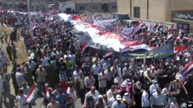 In this photo released by the Syrian official news agency SANA, Syrian pro-government protesters carry national flags along with pictures of Syrian President Bashar Assad during a rally in support of the reform program in the border town of Quneitra, Syri