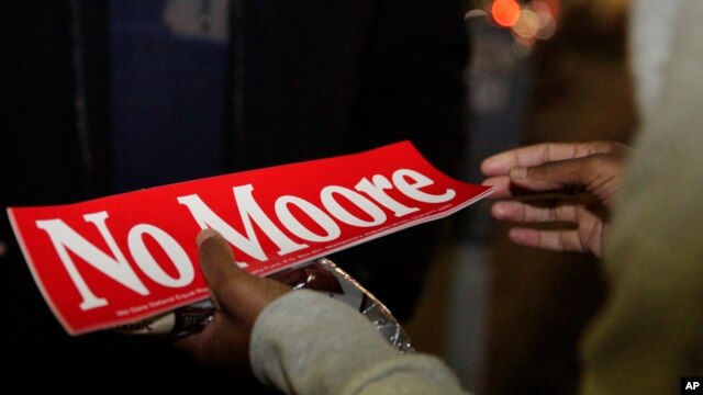 Tori Sisson, right, receives a gift of chocolate and a "No Moore," sticker, named after Roy Moore, from a supporter, near the Montgomery County Courthouse Sunday, Feb. 8, 2015.