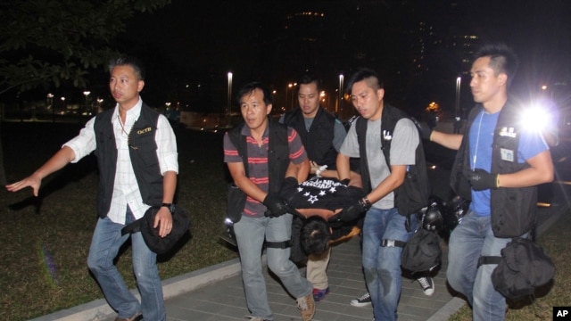 2014年10月15日，香港警察和抗议者在港府总部附近发生冲突后，便衣警察把抗议者曾健超抬出抗议地点。