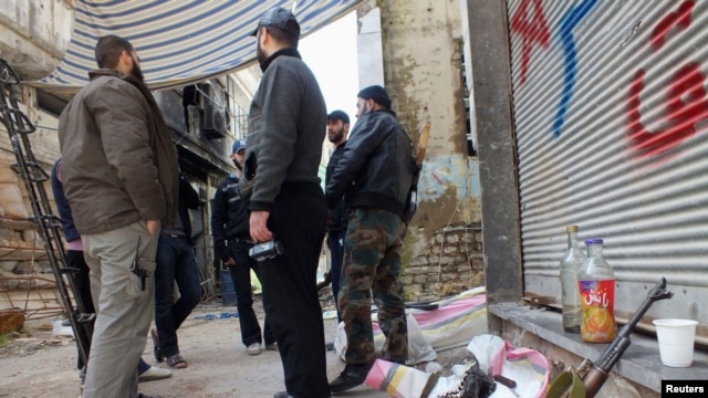 Free Syrian Army fighters stand by their weapons in the besieged area of Homs, March 9, 2013.
