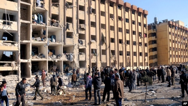 Warga Suriah berkumpul di dekat lokasi ledakan di Universitas Aleppo, Suriah, 15 Januari 2013. (AP Photo/SANA). Jumlah korban dalam ledakan ini dilaporkan mencapai 83 orang tewas dan lebih dari 150 orang lainnya luka-luka.