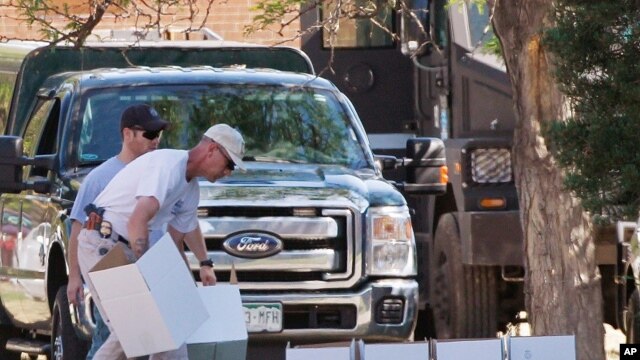 ATF agent arranges boxes for evidence in front of the apartment of James Holmes in Aurora, Colorado, July 21, 2012. 