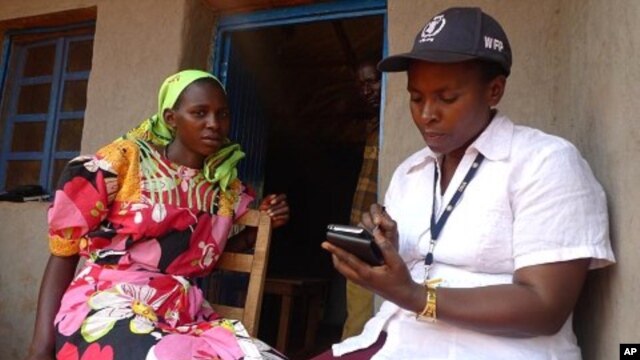 A WFP field monitor assistant conducts a food security survey with a Burundian resident in Bihogo village, using a personal digital assistant (PDA) to collect the data