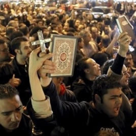 Egyptian Muslims and Christians raise a copy of the Quran and a Cross in Shubra district, Cairo, Egypt, Saturday, Jan.1, 2011 to protest against the terrorist attack on a Coptic Christian church in the northern Egyptian city of Alexandria.