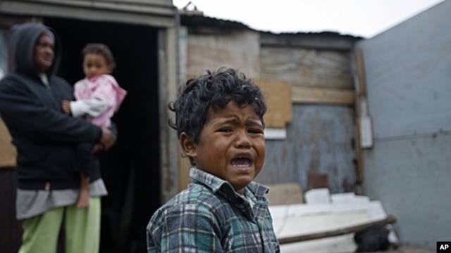 A boy reacts, in front of a house in a township on the outskirts of Cape Town, South Africa. Thousands of South Africans live without running water in their houses and without electricity. (2010 file photo)